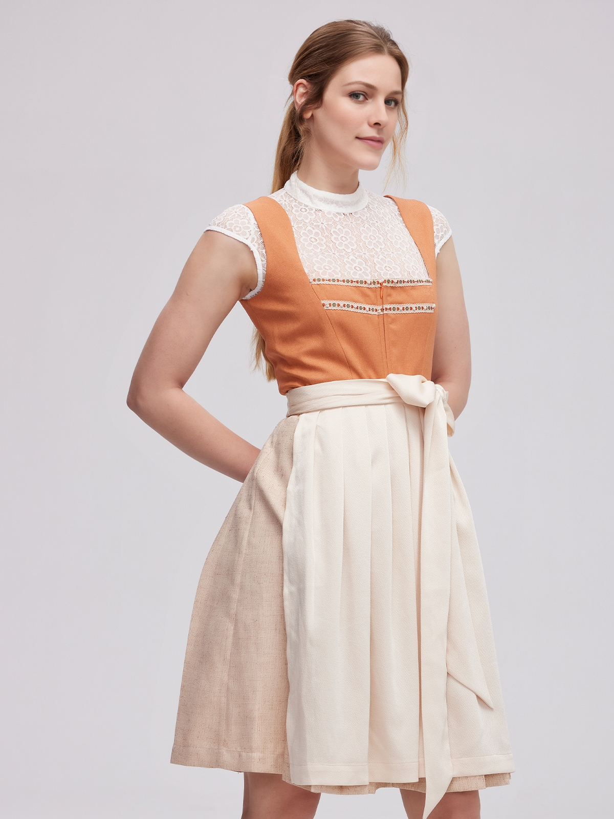 Frau in orangem Dirndl auf einer Wiese