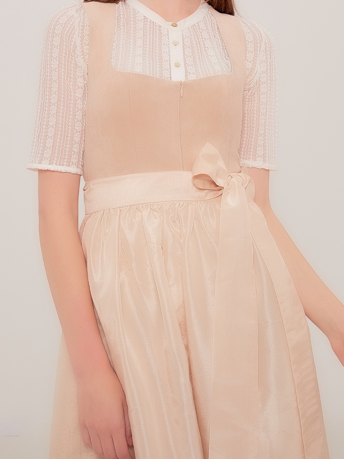 Ein beiges Dirndl mit traditioneller Schürze und Spitzenbluse